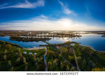 Top view of the beautiful Samarskie Plavni on the Dnieper with a village nearby in the warm evening light. Aerial panoramic drone shot