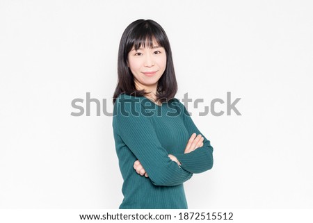 A smiling woman with her arms crossed in front of a white background shot in the studio