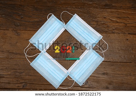 A medical mask and numbers 2021 on wooden background.