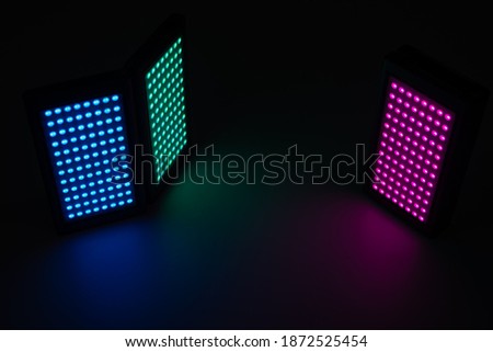 RGB mobile APP controlled LED constant light for video and photography shooting on a white background. The LED flash is photographed on reflected surface. 