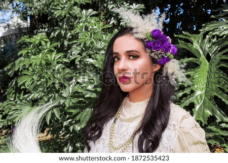 A closeup shot of a young Hispanic female with flowers in her hair standing outdoors