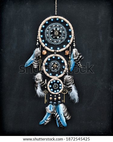 Beautiful handmade boho dreamcatcher with feathers and beads against black. Mystic background with dream catcher, esoteric and occult concept