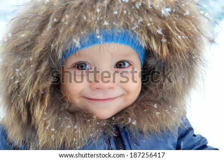 Smiling little boy portrait close-up in the snow