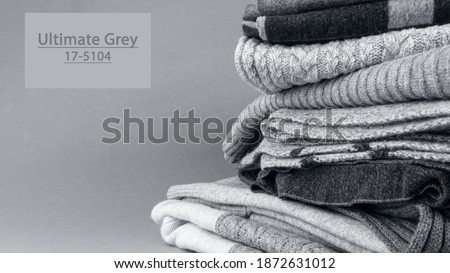 Close-up of knitted fashionable grey wool textured cloth, toned in ultimate grey, Pile of warm sweaters, scarfs. Demonstrating of trendy color 2021. Banner