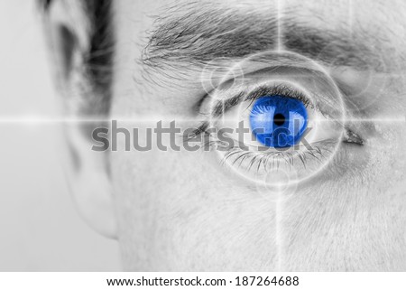 Vision concept with a greyscale image of a mans eye with a crosshair focused on his iris which has been selectively colored blue. Royalty-Free Stock Photo #187264688