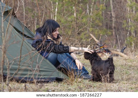 Woman with a dog resting at camp in the forest