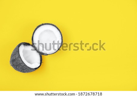 Top view of halved ripe gray colored  coconut on bright yellow background. Trendy colors 2021 year.  Summer concept. Minimal flat lay.Place for text