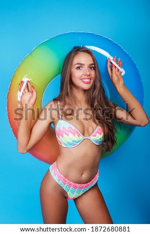 Young woman in bikini with inflatable standing on blue background