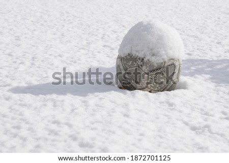 A soccer ball isolated on football ground with fresh snow in the playground. snow and winter sports concept. 