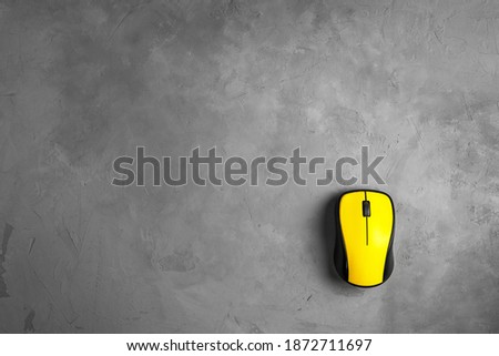 bright yellow computer mouse on a gray concrete background