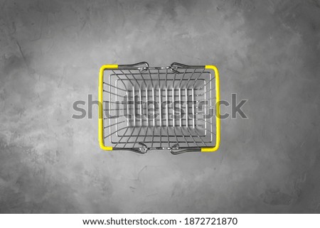 shopping basket with yellow handles on a gray background