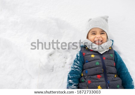 little boy with hat and gloves playing in the snow