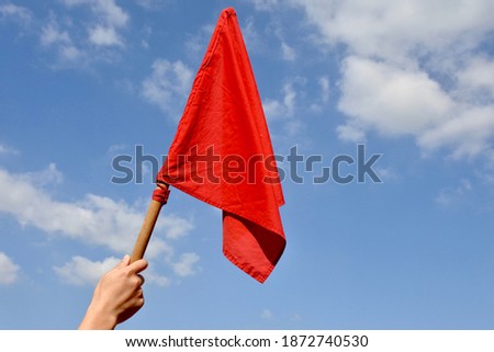 Red Flag | This is a hand waving the red flag in the air. This photo was taken in a sport event. However, as a red flag has many symbolic meanings, this photo would be useful for different occasions.