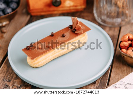 Traditional French eclairs with cream. Eclairs decorated with chocolate and berries on a plate.