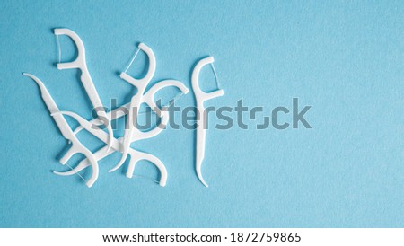 Dental floss picks on blue background. Soft floss picks. Dental picks. Plastic white dental toothpick with floss Royalty-Free Stock Photo #1872759865