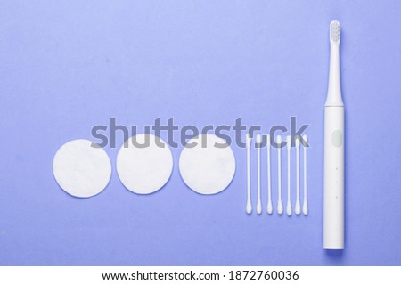 Flat lay composition of hygiene products. Toothbrush, cotton pads, ear sticks on purple background. Top view