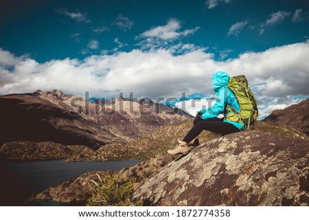 Woman backpacker  sit on beautiful winter mountain top rock