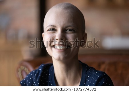Head shot portrait smiling hairless sick woman looking at camera, sitting on couch at home, overjoyed cancer patient struggling with oncology disease, successful treatment results, remission