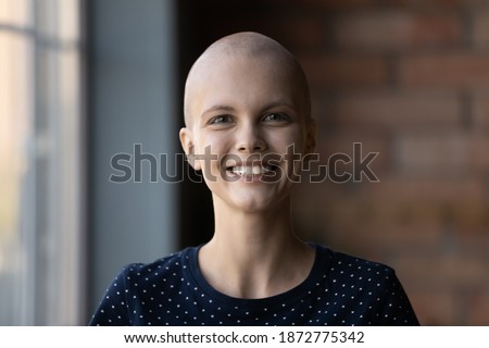 Head shot portrait smiling hairless woman looking at camera, happy young female cancer patient struggling with oncology disease, excited by successful treatment results, remission and recover
