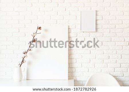 mock up poster frame with cotton branch on white brick wall background