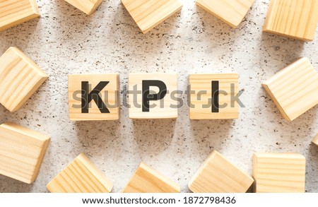 The word KPI consists of wooden cubes with letters, top view on a light background.