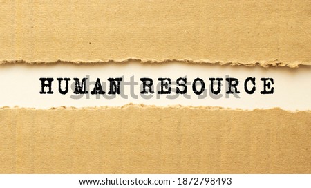 Text HUMAN RESOURCE appearing behind torn brown paper. Top view.