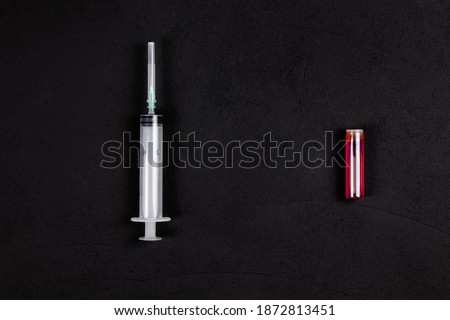 Ampoule with the vaccine and syringe on black background. Pndemic