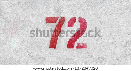 Red Number 72 on the white wall. Spray paint.