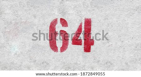 Red Number 64 on the white wall. Spray paint.