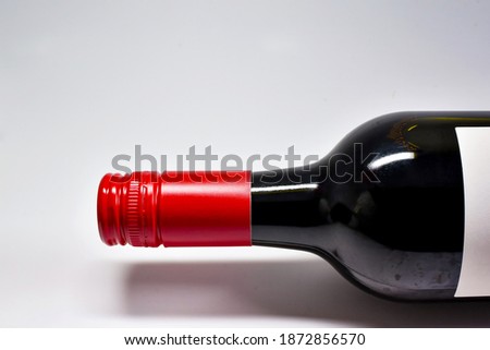 Close up of the top and neck of a screw cap bottle of red wine on a plain white background. No people. Copy space. Royalty-Free Stock Photo #1872856570