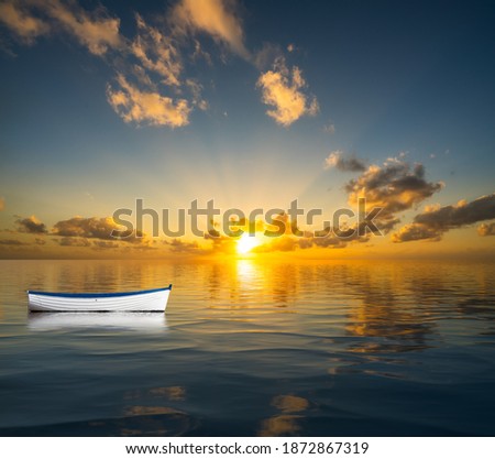 White rowing boat without people drifting on the open sea towards a sunset to illustrate leadership crisis Royalty-Free Stock Photo #1872867319