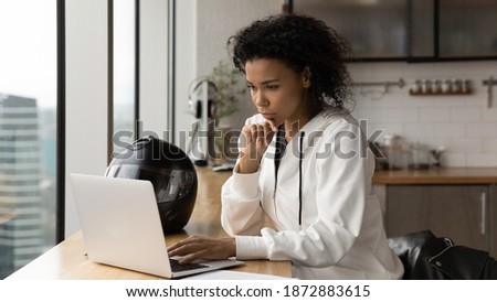 Banner view of young African American woman biker look at laptop screen working online at home office. Thoughtful female busy using modern computer, browse surf wireless internet. Technology concept.