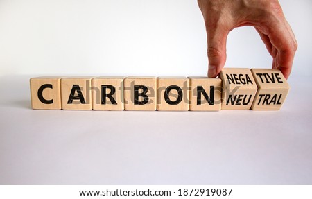 From carbon neutral to negative. Hand flips cubes and changes words 'carbon neutral' to 'carbon negative'. Beautiful white background, copy space. Business, ecological and carbon negative concept. Royalty-Free Stock Photo #1872919087