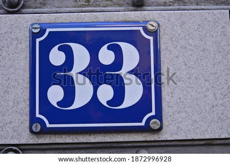 A blue house number plaque, showing the number thirty three (33)