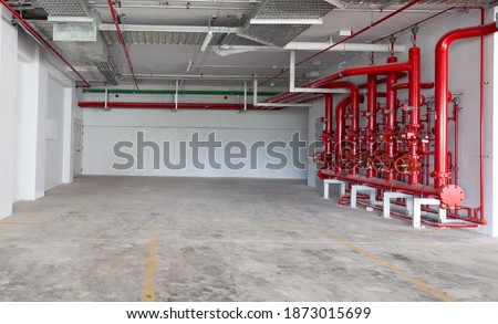 Parking garage interior, industrial building, hydrant with water hoses and fire extinguisher equipment , water pipe valve,pipe for water piping system control in industrial building.