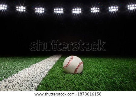 Baseball on a grass field with stripe and black background under lights 