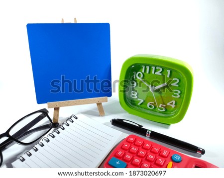 Copy space and text space on blue board with notebook,green clock,pen,glasses and calculator.Isolated on white background.Education and business concept.