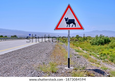 Road sign warning the driver about approaching a section of the road, where it is possible to enter the carriageway of large domestic animals and drive livestock