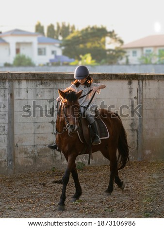 Asian school kid girl with horse ,riding or practicing horse ridding at horse ranch.
