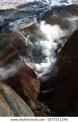 Mutnovsky volcano. A large snowfield on the mountainside. Steaming fumaroles in the crater of the active volcano. Archive photo, 2008