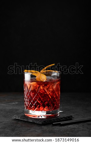 Classic Negroni Cocktail in a retro glass with ice and orange peel on a black background Royalty-Free Stock Photo #1873149016