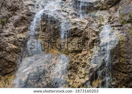 little waterfall and steep rocks in the mountains detail view while hiking