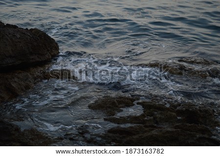 Sea waves crashing into rocks. Storm at the sea, dark, moody photo. Clear water, sharp rocks.
