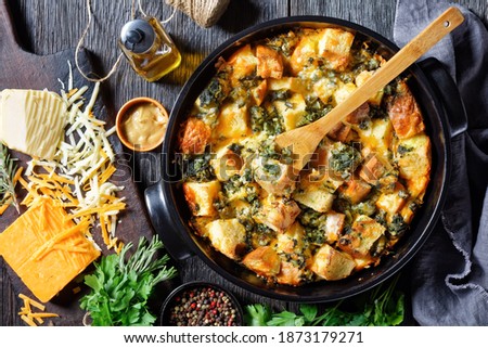 Italian spinach strata of soaked overnight cubed sandwich bread and baked with chopped spinach and shredded cheese with mustard served on a black baking dish on a wooden background, top view Royalty-Free Stock Photo #1873179271