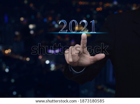 Businessman pressing 2021 text over blur colorful night light modern city tower and skyscraper, Happy new year 2021 calendar cover concept