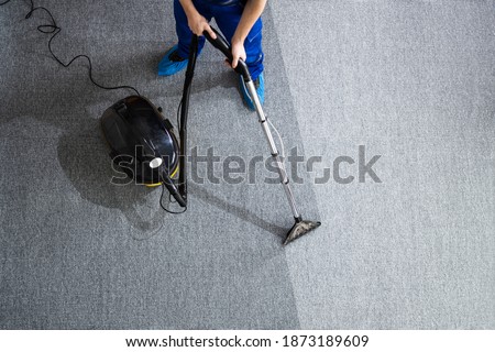 Janitor Cleaning Carpet With Vacuum Cleaner At Home Royalty-Free Stock Photo #1873189609