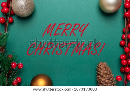 Merry Christmas inscription on horizozntal banner with copy space on green background with red berries, viburnum, xmas ornaments, baubles, fir branch and pine cone. Top view.