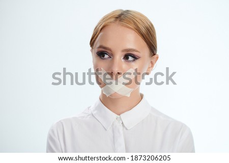 Portrait of girl with tape on mouth isolated on studio background