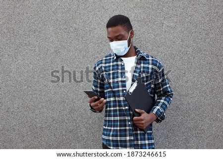 Horizontal photo of handsome employee of real estate agency, isolated against background of wall, holding documentation, and communicating with clients in phone. People, business and sales concept.