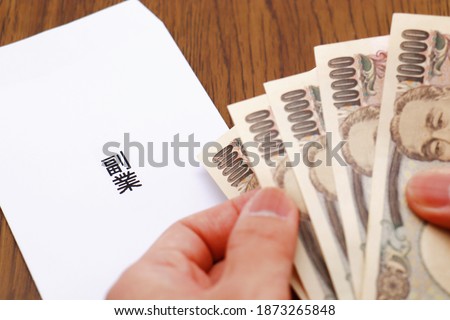 A white envelope with Japanese characters and five 10,000 yen bills. Total of 50,000 yen. The image of a company employee's supplementary income. Translation: side job. Royalty-Free Stock Photo #1873265848